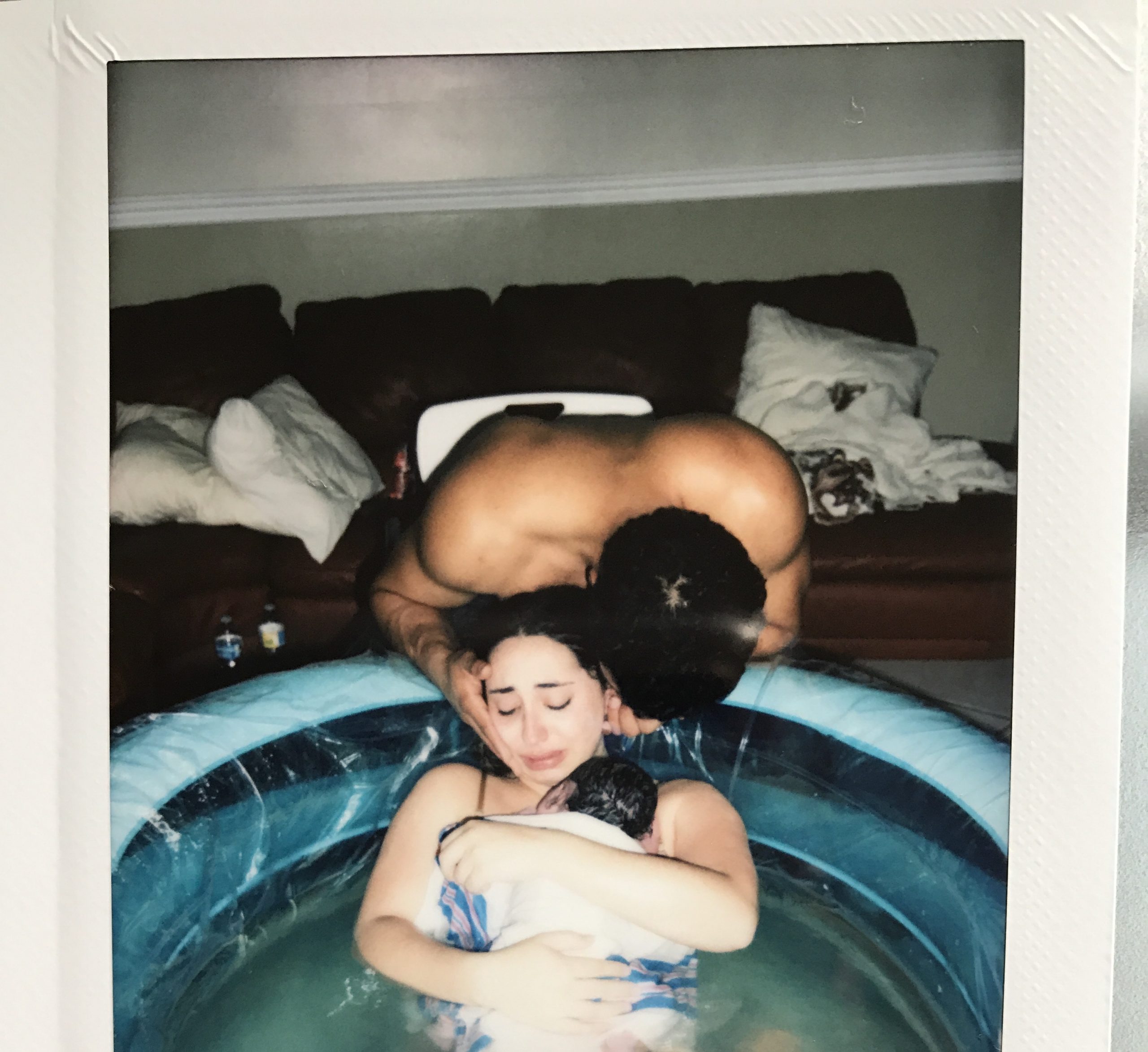 mother and father holding newborn in birth pool
