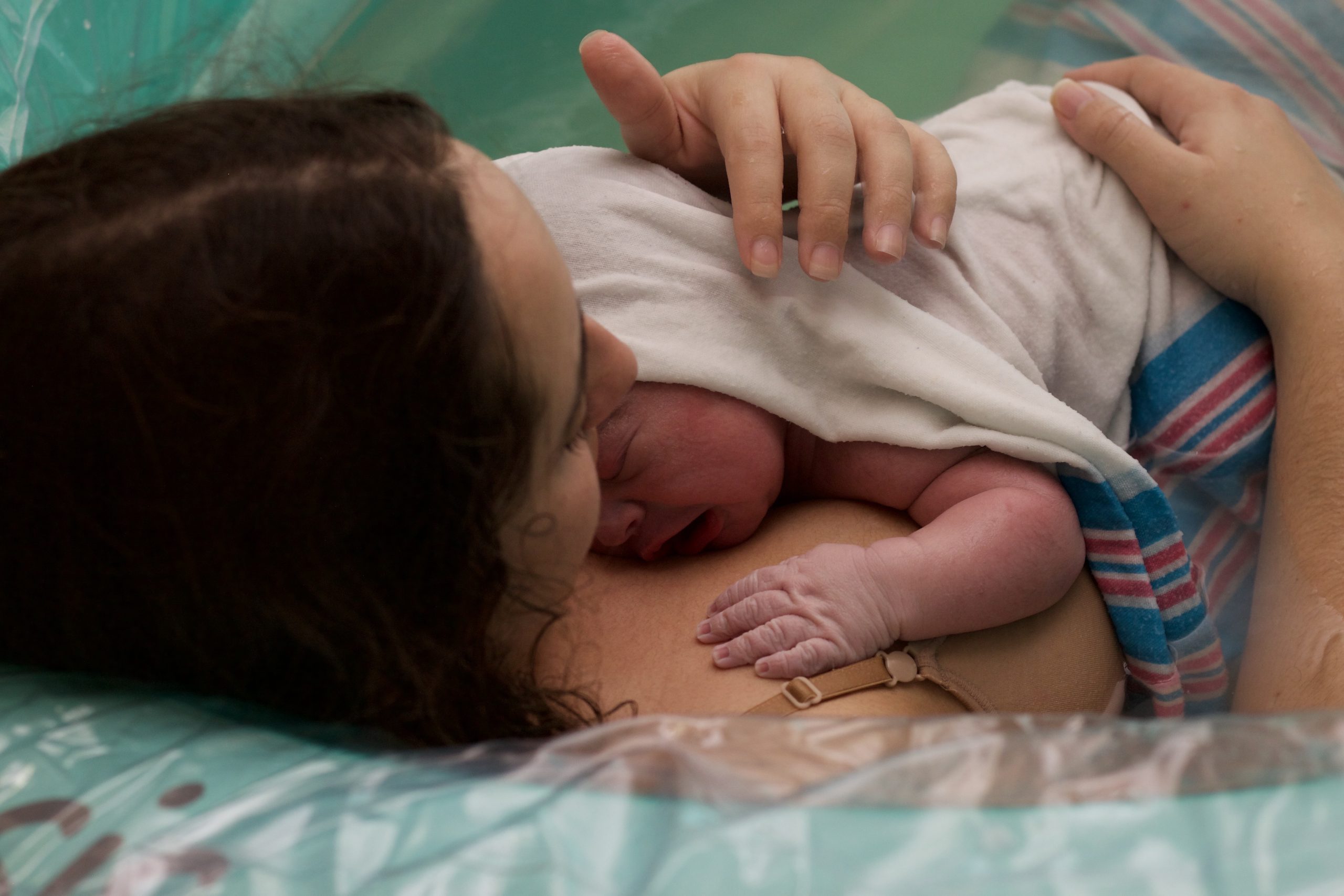 mother holding baby wrapped in blanket after water birth