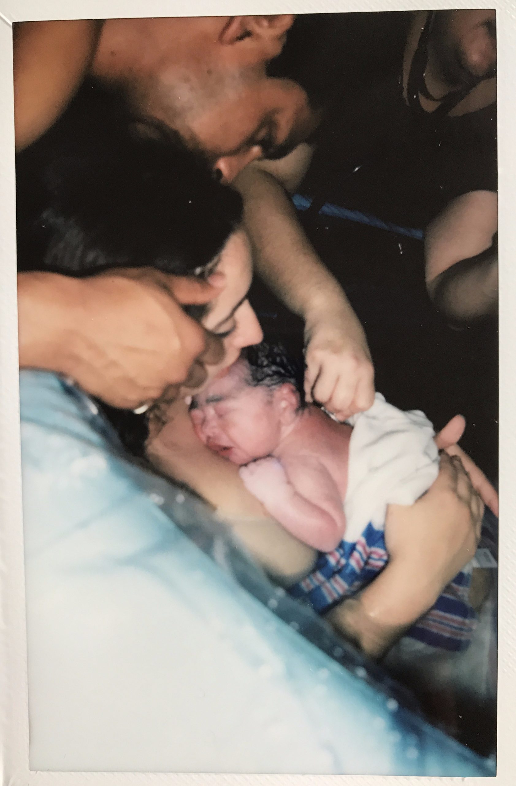 mother holding newborn in birth pool with father