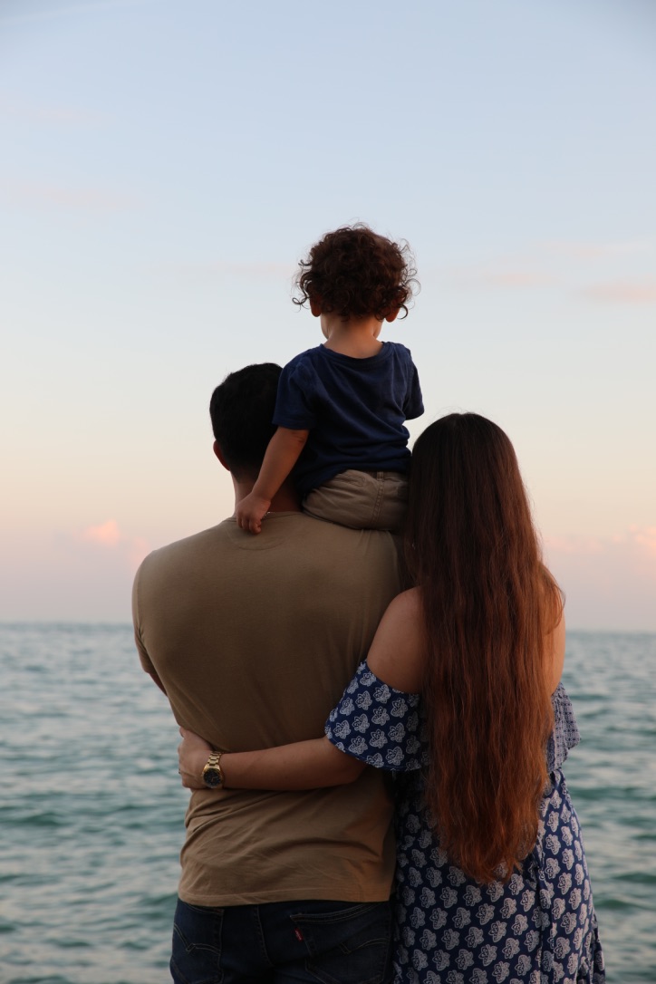 family of three looking out to the ocean at sunset